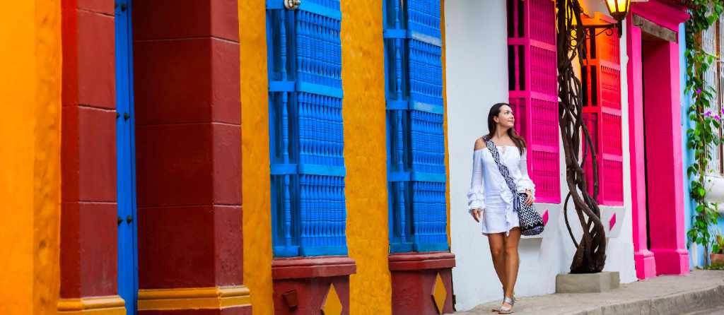 Beautiful woman on white dress walking alone at the colorful streets of the colonial walled city of Cartagena de Indias